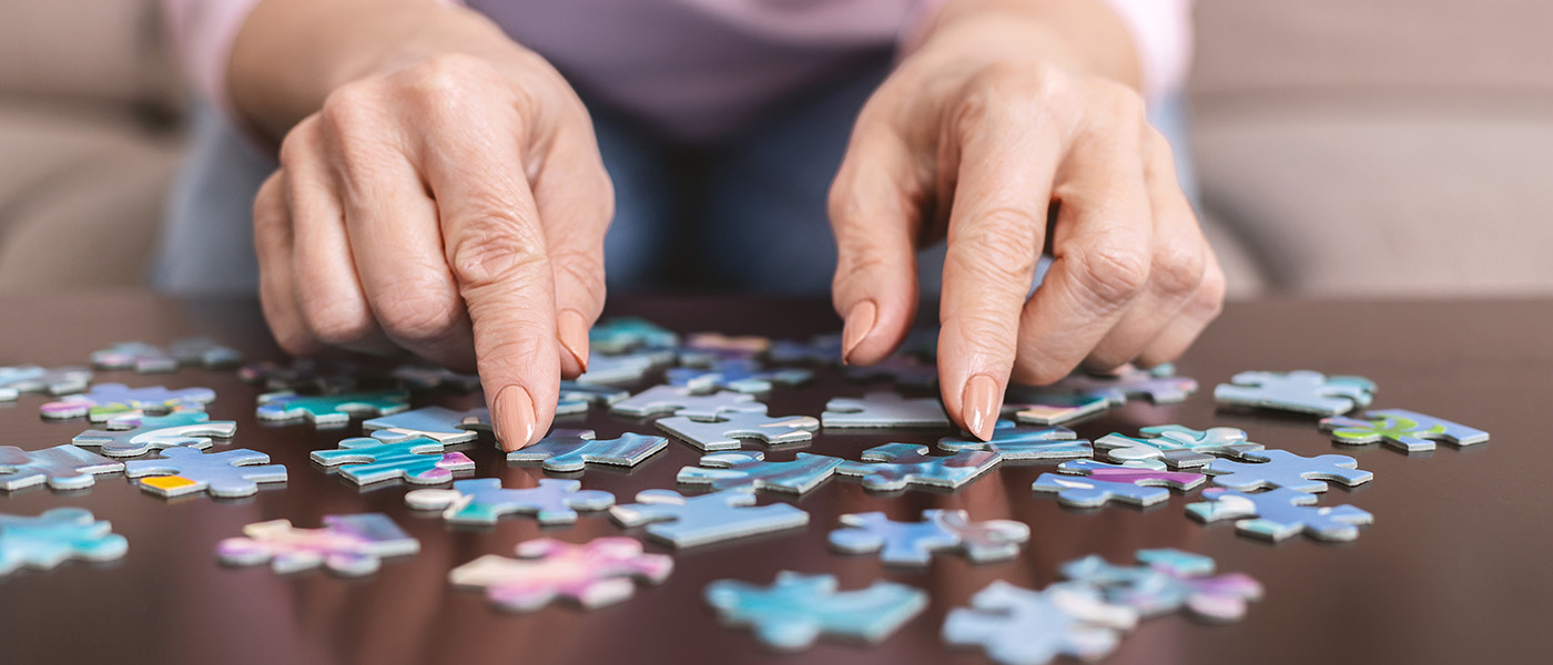 senior woman hands with puzzle pieces